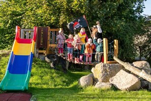 A playground with a slide, climbing structure, and a pirate-themed flag. - Holiday apartment in Fehmarn with Wi-Fi (Fehmarn)