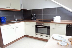 A modern kitchen with white cabinets, a built-in oven, a coffee maker, and a toaster. - Holiday apartment with 2 bedrooms (Schramberg-Tennenbronn)