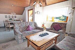 A cozy living room with patterned sofas, a wooden coffee table, and a dining area with a table and chairs. - Holiday apartment with 2 bedrooms (Schramberg-Tennenbronn)