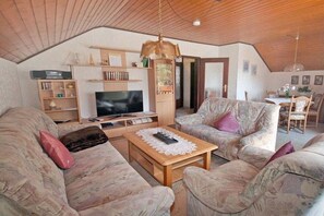 A cozy living room with a television, sofas, a coffee table, and a dining area with chairs. - Holiday apartment with 2 bedrooms (Schramberg-Tennenbronn)
