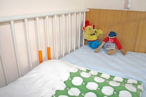 A crib with a white mattress and a green polka-dotted blanket. - Holiday apartment with 2 bedrooms (Schramberg-Tennenbronn)