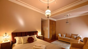 Een hotelkamer met een groot bed, nachtkastjes, een sofa en een kroonluchter.