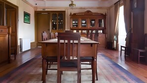 Een kamer met een houten eettafel, stoelen, een kroonluchter en een kast met glazen deuren.
