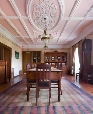 A room with a wooden dining table, chairs, a chandelier, and a cabinet with glass doors.
