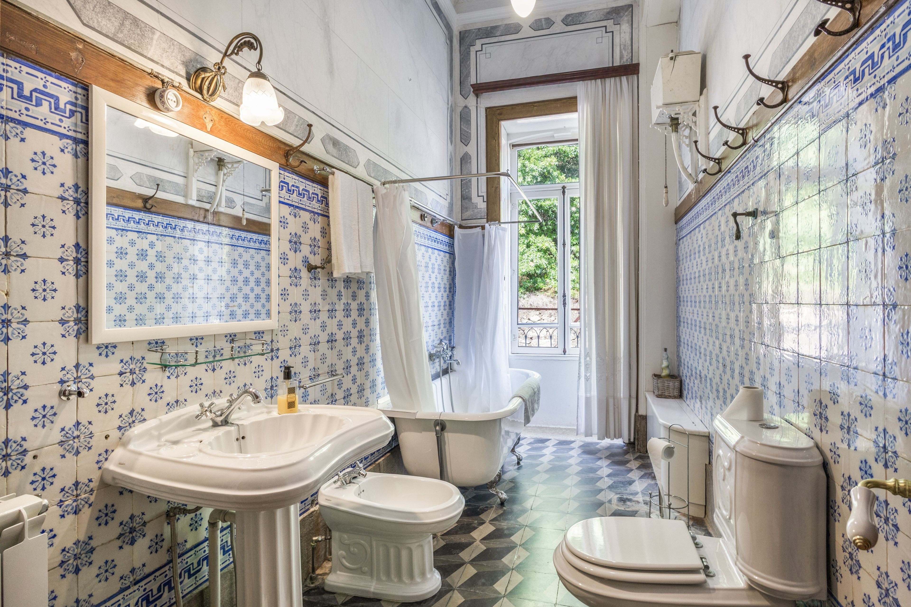 A bathroom with a bathtub, a sink, and a toilet, all with blue and white patterned tiles.