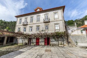 Un edificio storico con facciata in tegole, diverse finestre e una porta rossa.
