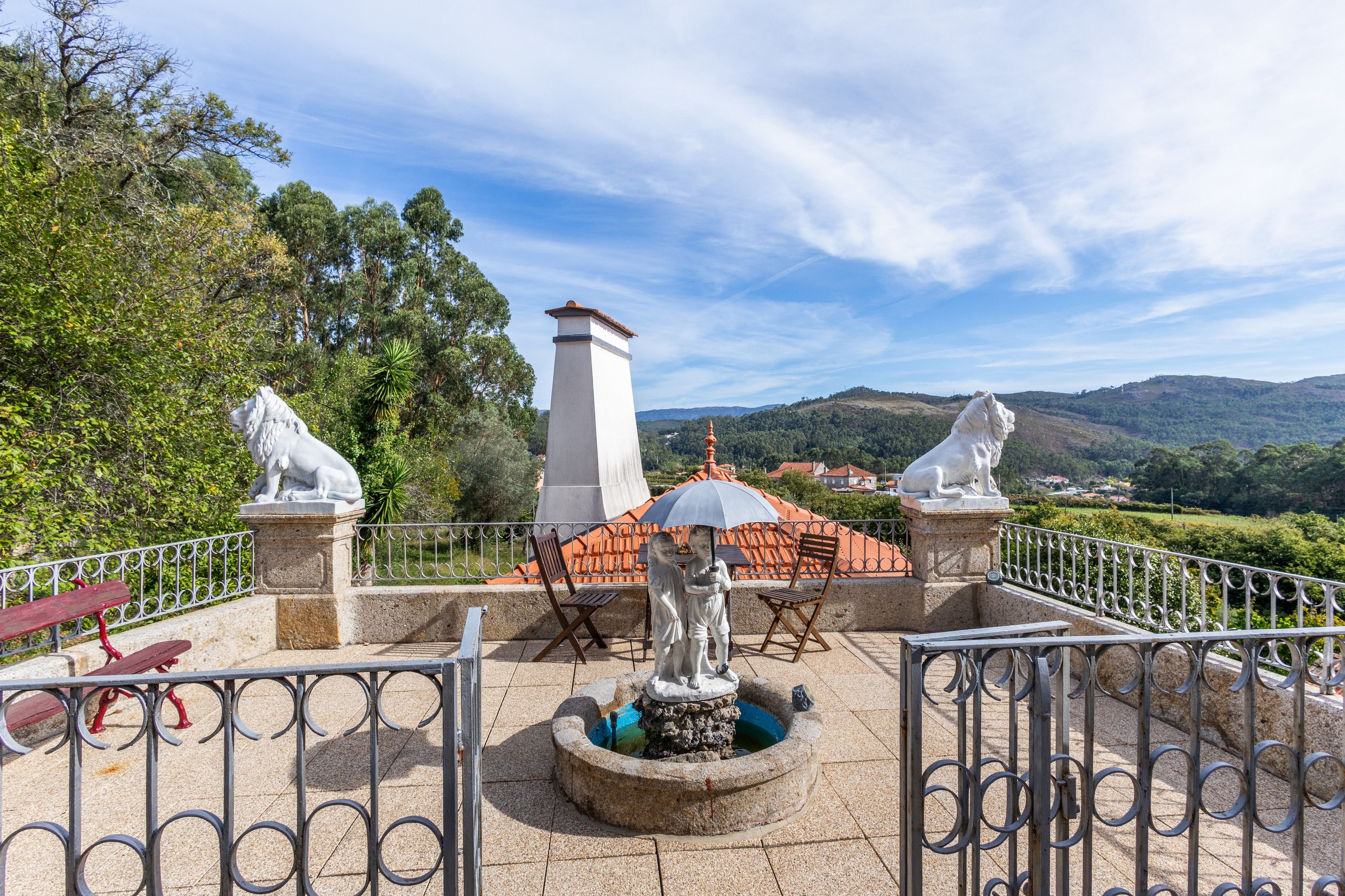 Un jardin agrémenté de statues, d’une fontaine et offrant une vue sur les collines.