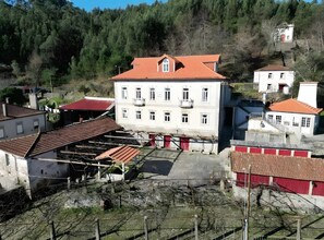 A white building with a red roof, surrounded by trees and other buildings.
