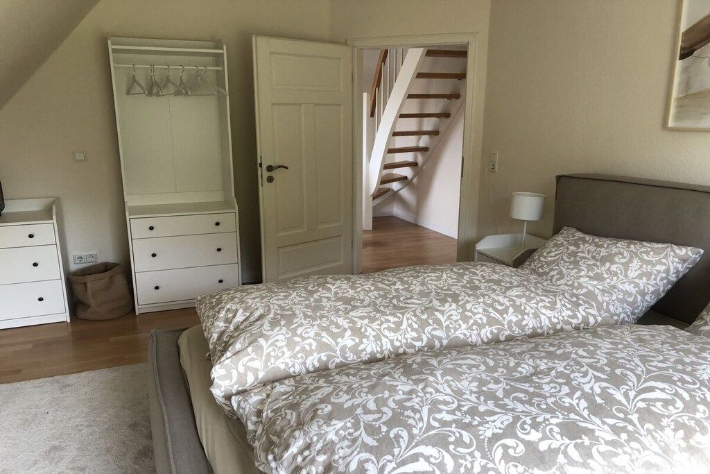 A bedroom with a bed, a wardrobe, a small bedside table, and a staircase leading to another floor.