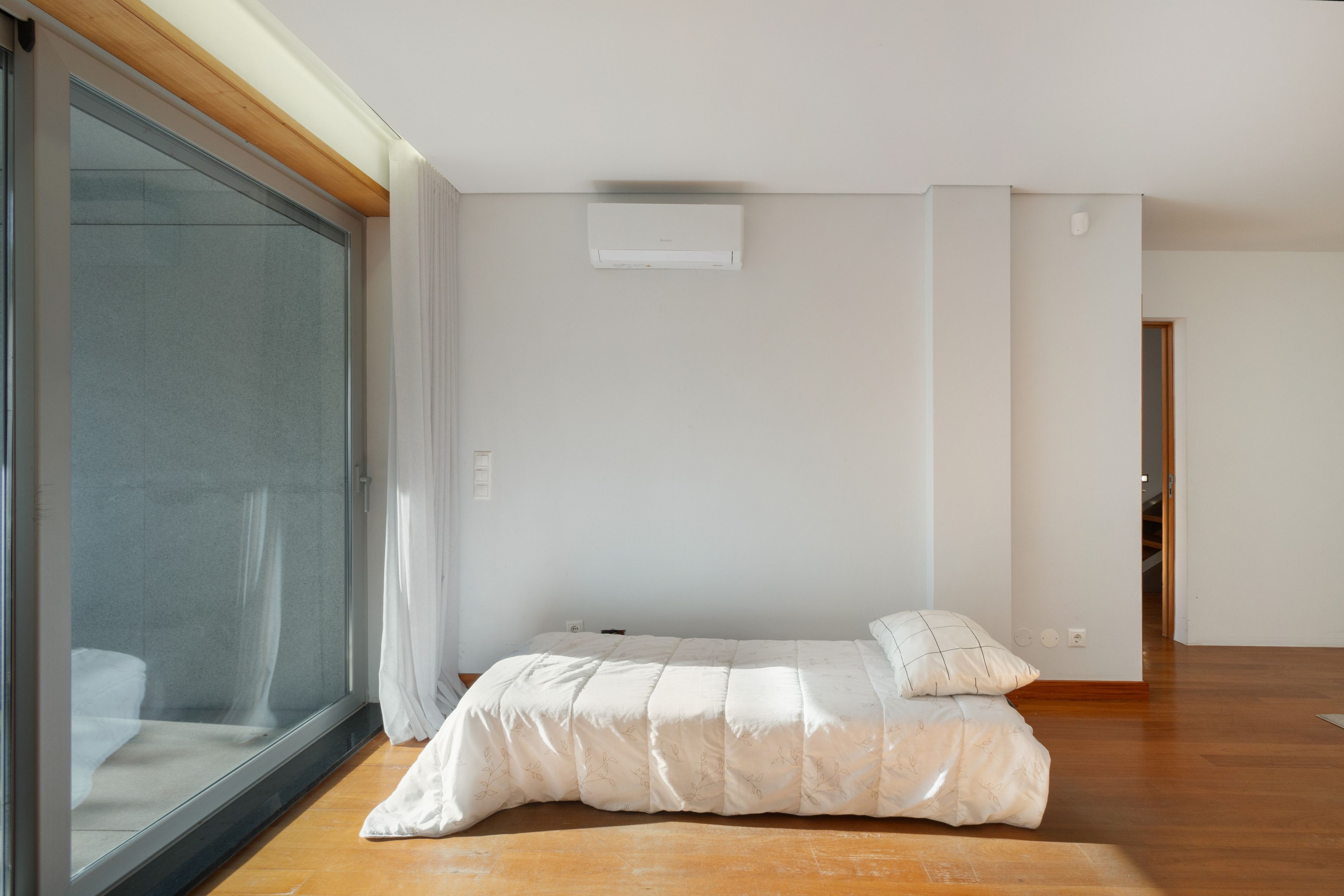 Ein Schlafzimmer mit einem Bett, einer Schiebetür und einer weißen Klimaanlage an der Wand.