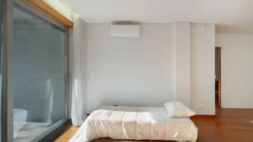 Una camera da letto con un letto, una porta finestra e un condizionatore d'aria bianco a parete.