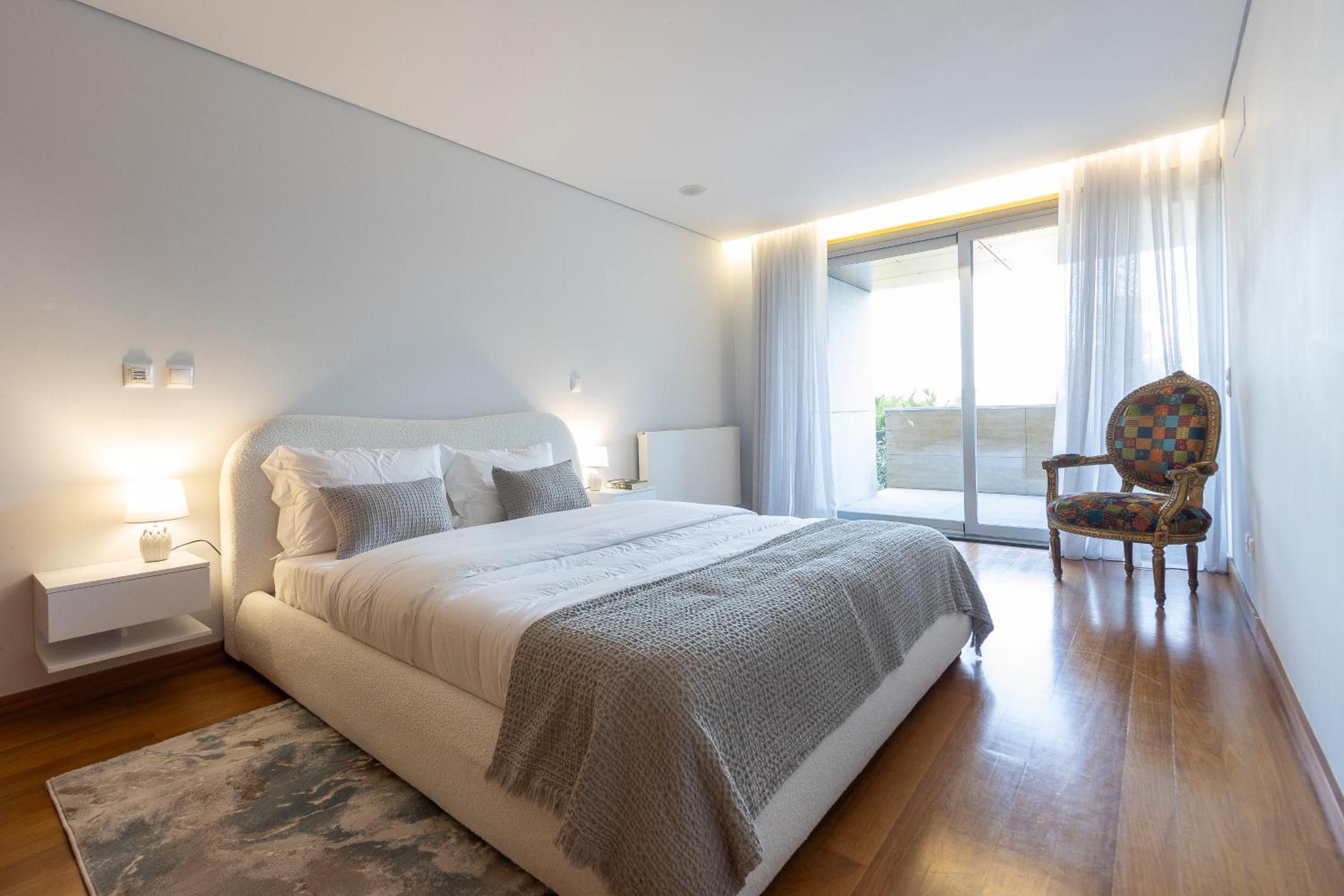 Un dormitorio moderno con una cama grande, una silla y vistas al exterior.