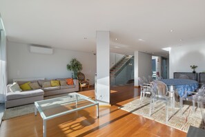 A modern living room with a sofa, coffee table, and dining area with chairs. - Villa 'Casa São Francisco' (Montanha de Santa Luzia)