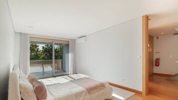A bedroom with a large bed, a sliding glass door to a balcony, and a fire extinguisher on the wall.