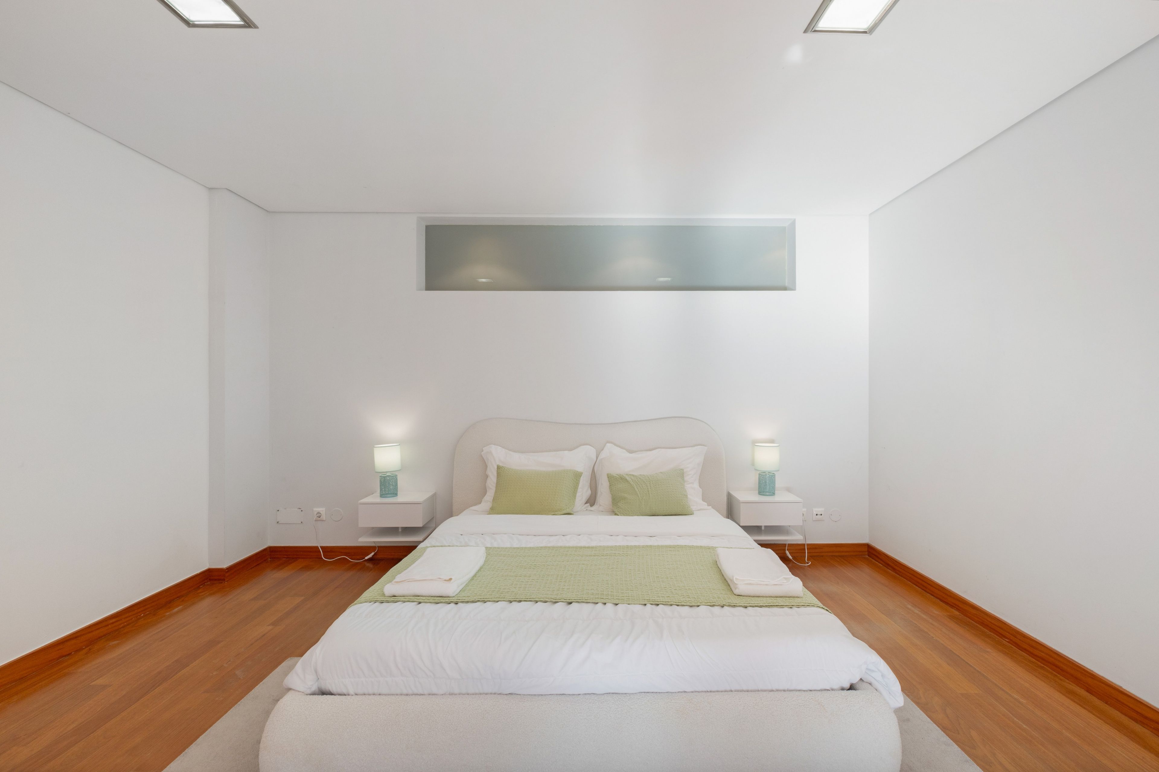 Una camera da letto con un letto, comodini e una lampada a parete.