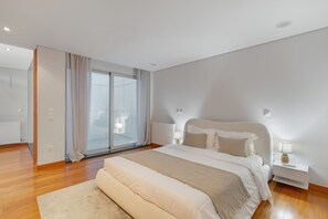A modern bedroom with a large bed, a nightstand, a lamp, and a view through a glass door. - Villa 'Casa São Francisco' (Montanha de Santa Luzia)