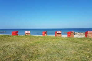 A beachside view with red beach huts and a clear blue sky. - Holiday apartment with 2 bedrooms (Schönhagen)