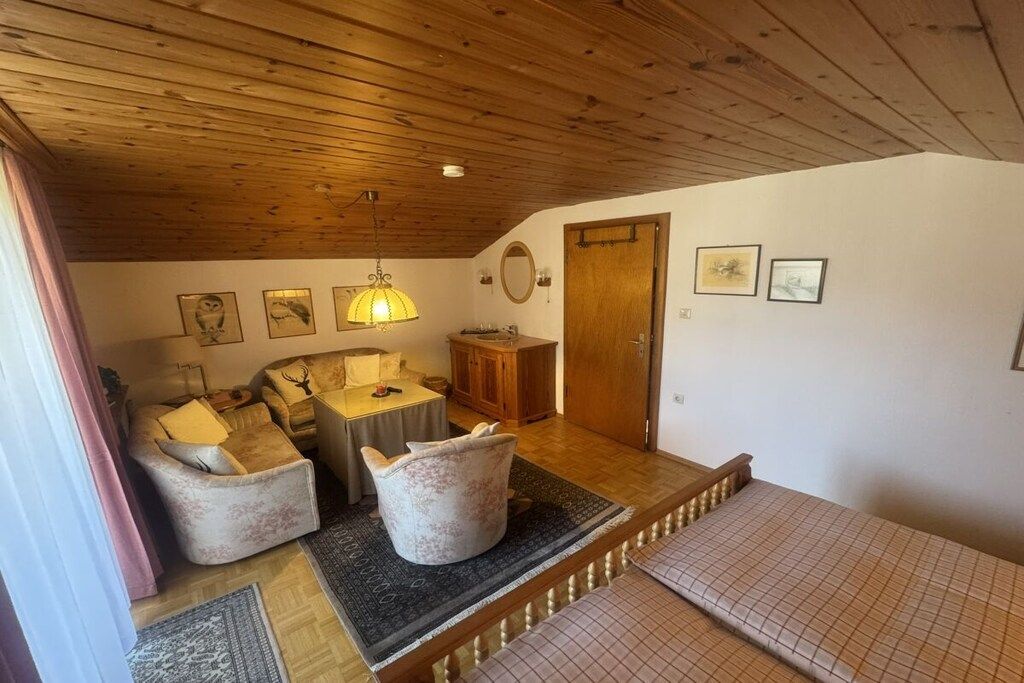 A cozy room with a wooden ceiling, a sofa, a table, and a bed.