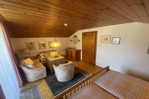 Ein gemütliches Zimmer mit Holzbalkendecke, einem Sofa, einem Tisch und einem Bett.
