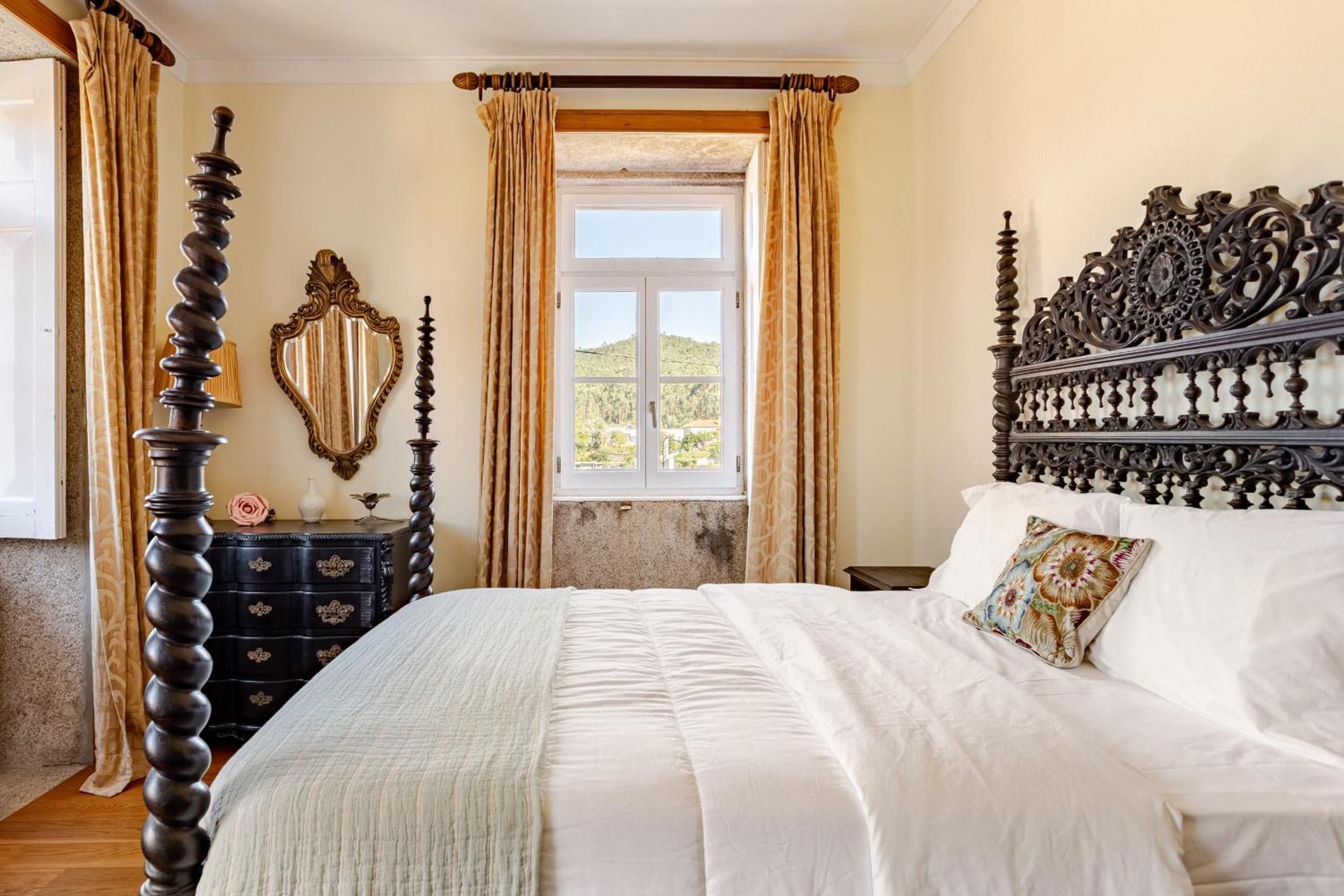 A bedroom with a large bed, ornate headboard, and curtains.