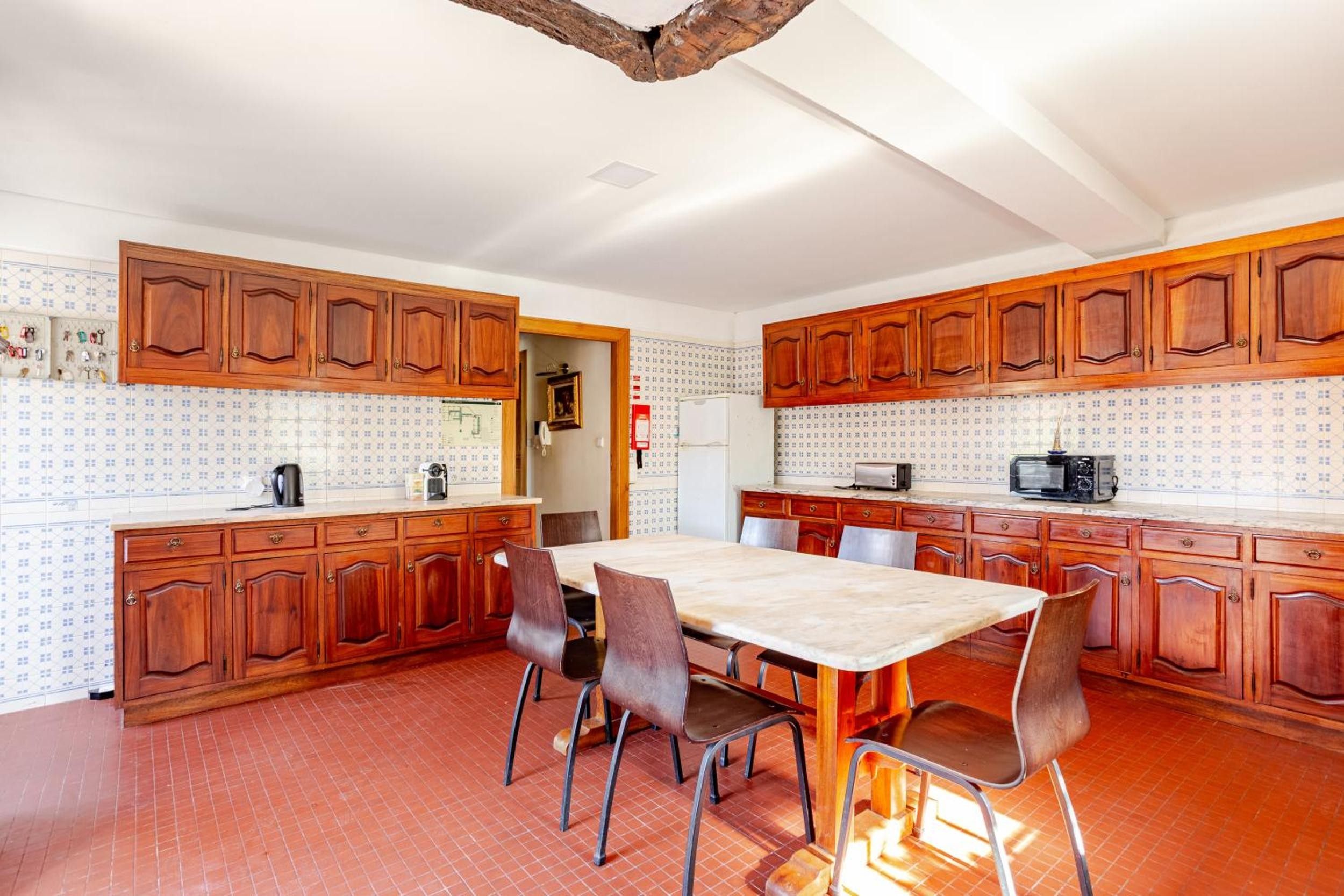 A kitchen with wooden cabinets, a dining table with chairs, and a tiled backsplash.