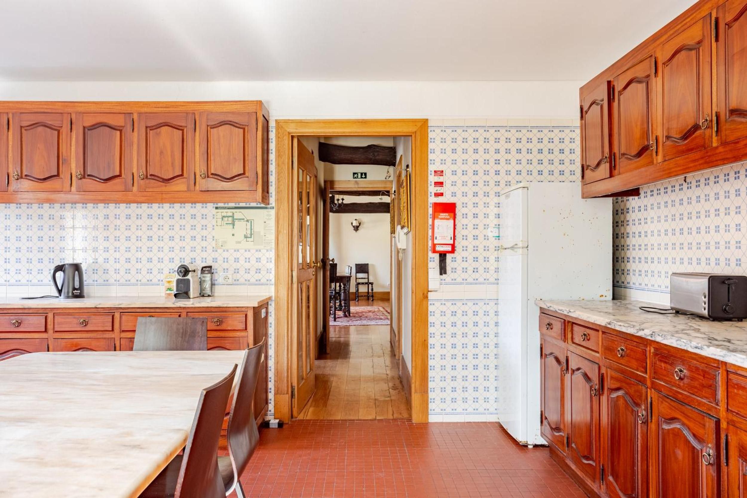 Une cuisine avec des meubles de rangement en bois, une table à manger et un réfrigérateur.