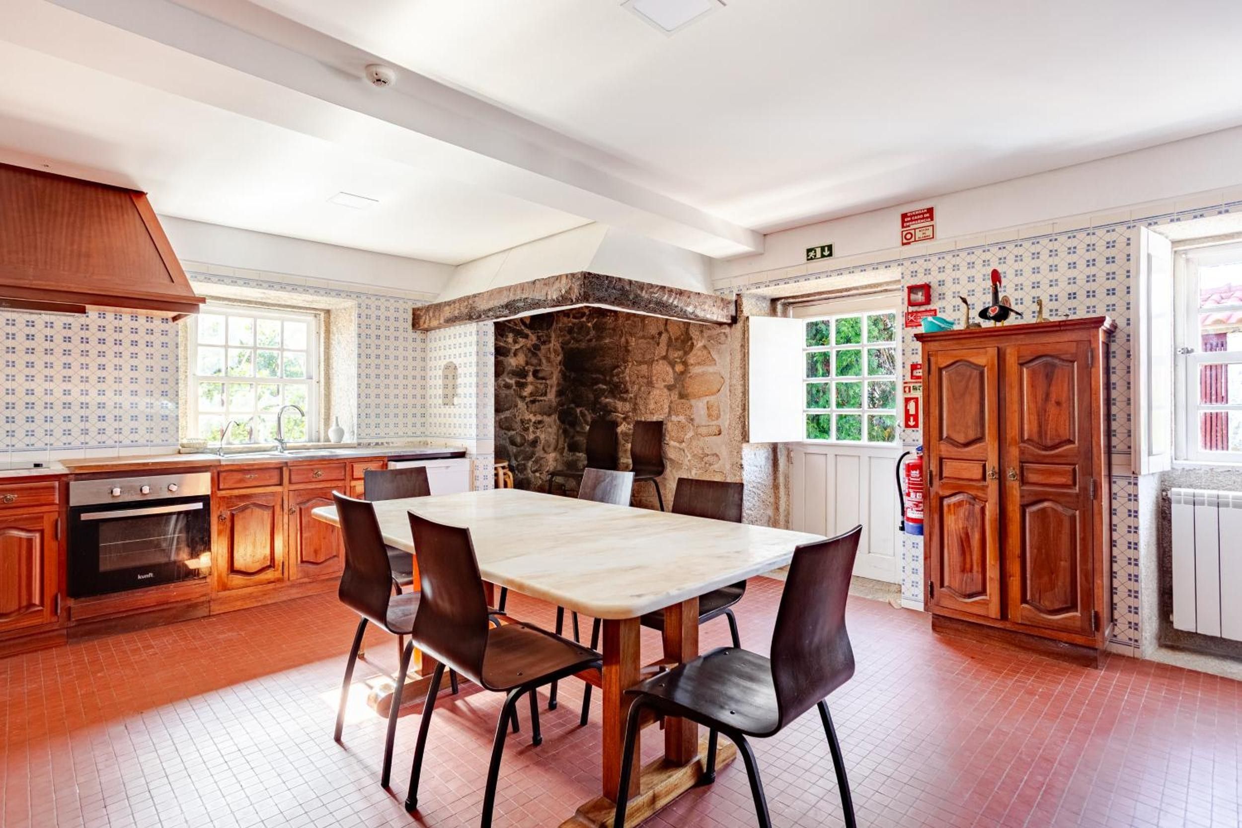 A kitchen with a stone wall, wooden cabinets, and a tiled backsplash.