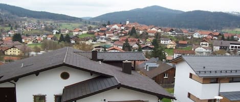 Un barrio residencial con casas, un automóvil y montañas al fondo.