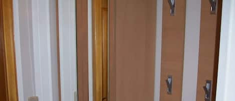 A hotel room with a wooden door, a mirror, and a light switch on the wall.