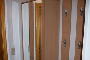 Ein Hotelzimmer mit Holztür, Spiegel und Lichtschalter an der Wand.