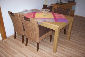 Une table à manger recouverte d’une nappe à motifs, entourée de chaises en osier.