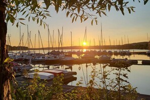 Un puerto deportivo con varias embarcaciones amarradas, rodeado de vegetación y un cielo despejado.