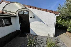 A white brick house with a dark brown door, a small garden with gravel and plants, and a clear blue sky. - Zeewind Bredene - Belgian coast (Bredene)