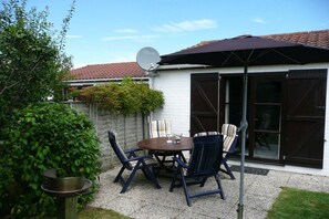 An outdoor patio with a round table and chairs, a satellite dish, and a large umbrella. - Zeewind Bredene - Belgian coast (Bredene)