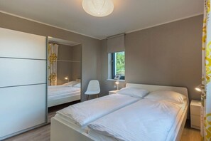 A bedroom with a bed, a chair, a bedside table, and a mirror. - House on the dike, harbor 3a H8 ground floor 48m² (Ostseebad Prerow)