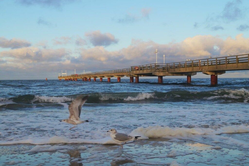 Un muelle se adentra en el agua, con olas chocando contra él.