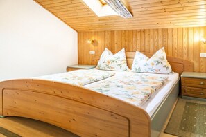A wooden-paneled bedroom with a bed, two nightstands, and a skylight. - Almgut Farm || Faistenau (Faistenau)