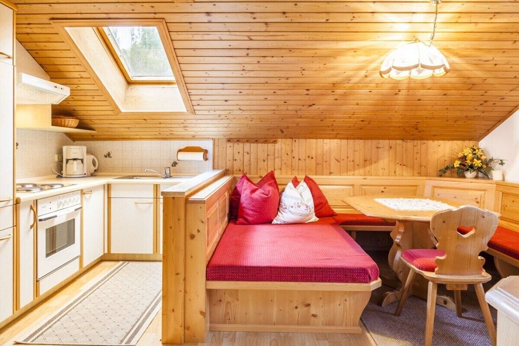 Eine kompakte Küche mit eingebauter Bank und Sitzgelegenheit, einem Esstisch und einem kleinen Fenster.
