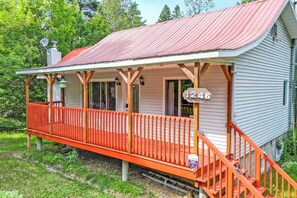 A single-story house with a porch, a red roof, and a mailbox.