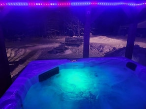 Un jacuzzi con vistas a un paisaje nevado y un banco al fondo.