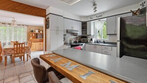 Cozinha moderna com área de bar, conjunto de jantar de madeira e vista para o exterior.