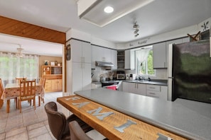 Une cuisine moderne avec un coin bar, un ensemble de salle à manger en bois et une vue sur l’extérieur.