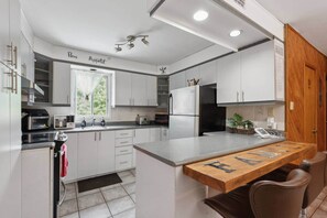 Una cocina moderna con gabinetes blancos, horno empotrado e isla de madera con pizarra.