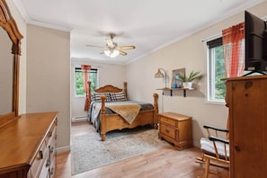 A bedroom with a bed, dresser, chair, and a ceiling fan.