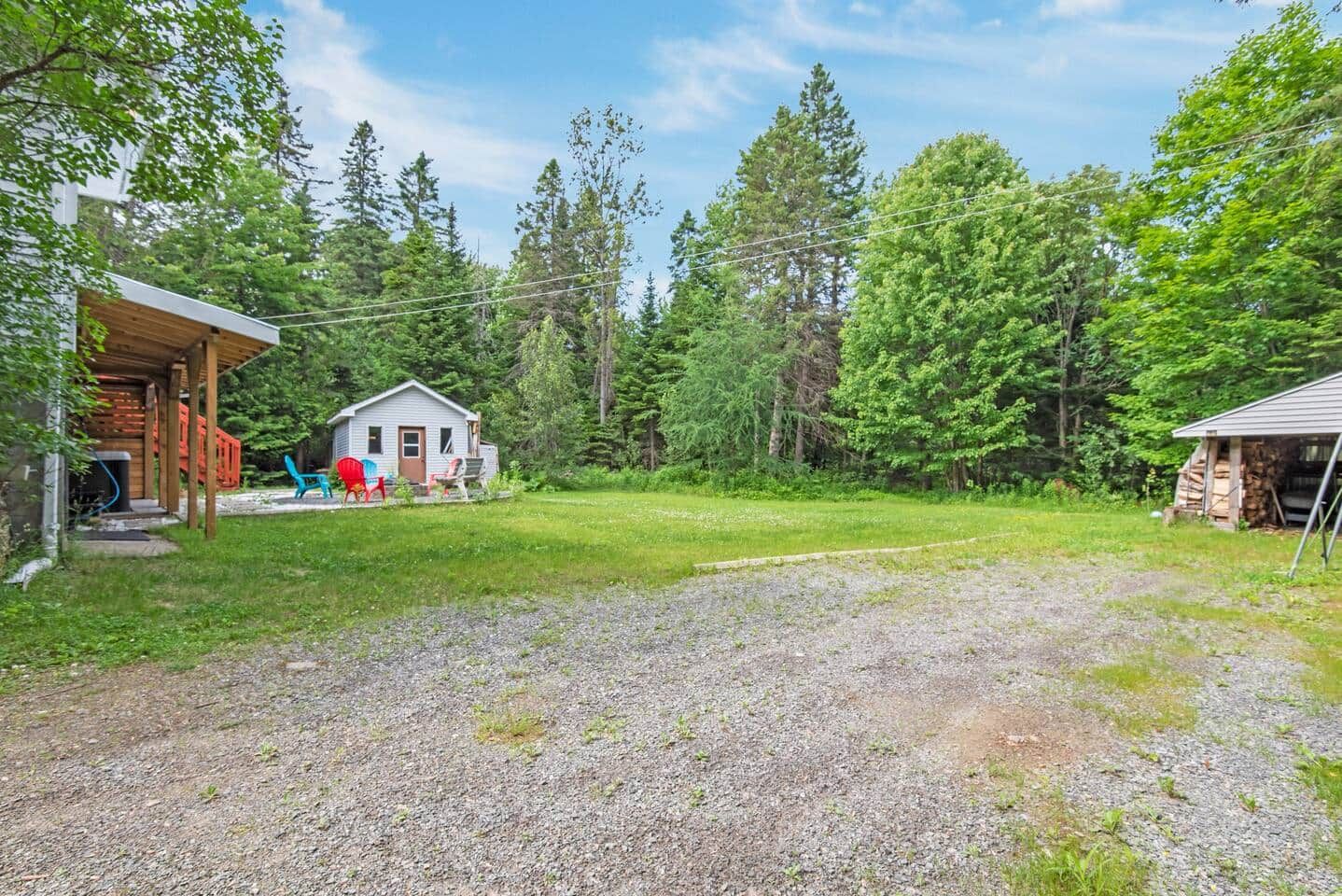 A residential property with a covered porch, a small house, and a gravel driveway.