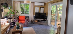 A living room with a sofa, television, and a view of the outdoors.
