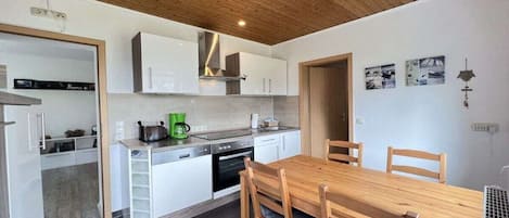 Una cocina moderna con armarios blancos, una mesa de comedor de madera y un horno empotrado.