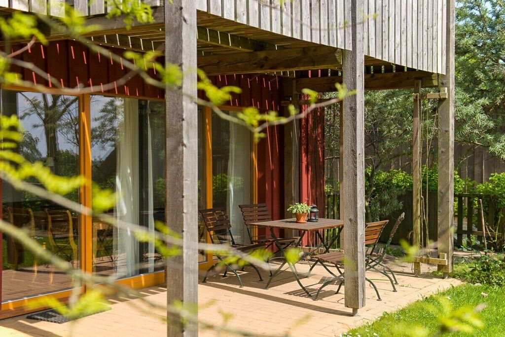 A wooden deck with a table and chairs, surrounded by glass doors and windows.