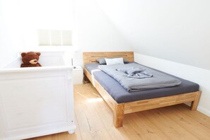 A bedroom with a wooden bed, a white nightstand, and a white dresser. - Holiday home in Glowe with swimming pool (Glowe)