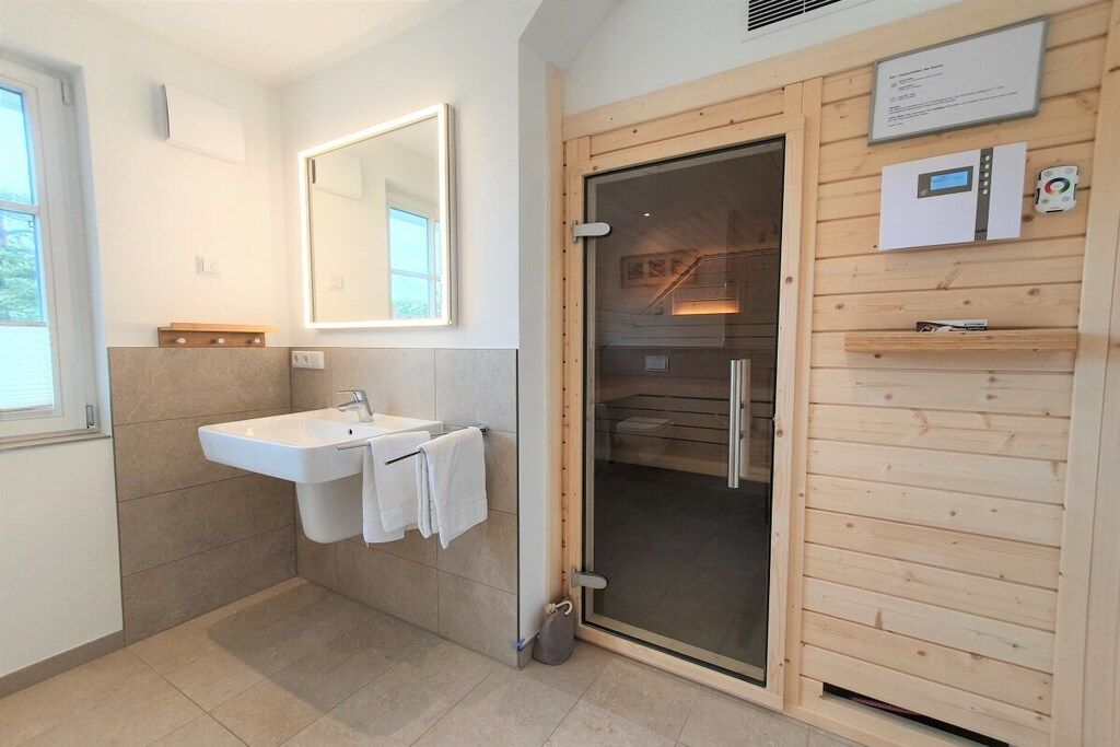 Een moderne badkamer met een wastafel, spiegel en douchecabine.